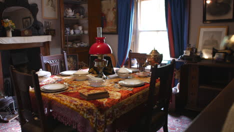 antique dining room set with ornate tablecloth and china, featuring a classic oil lamp