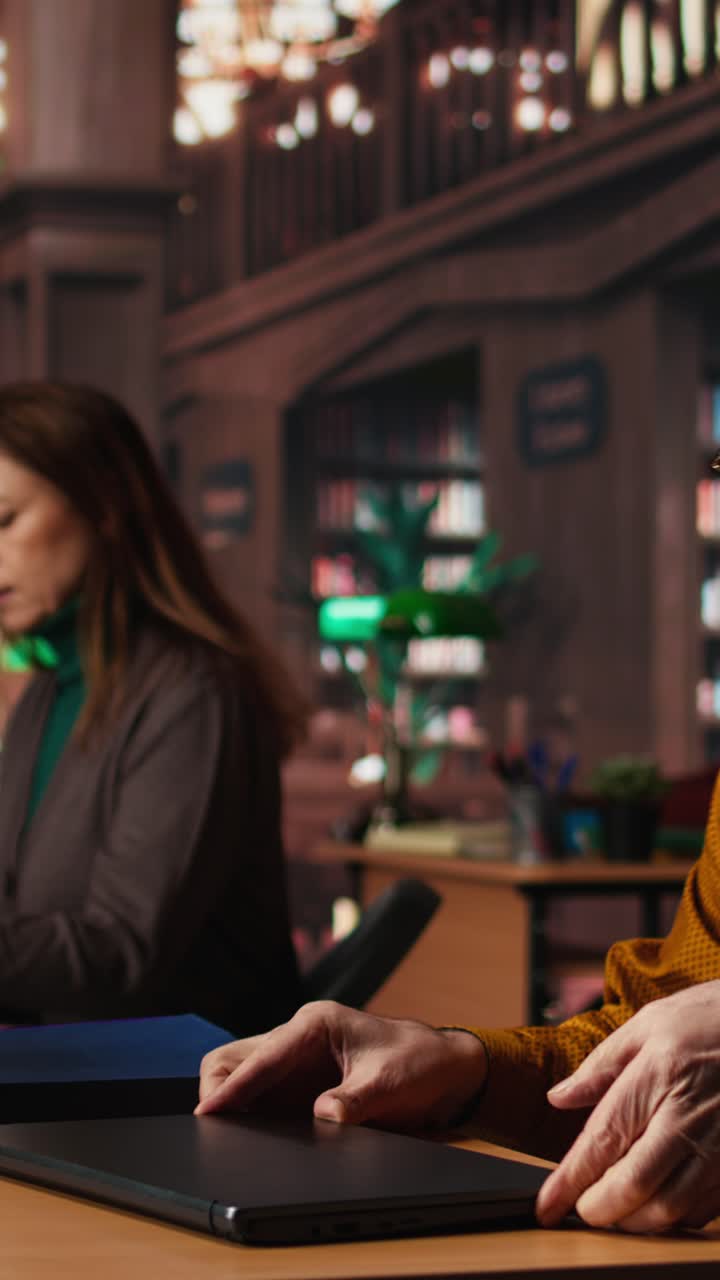Vertical Video Aged man student typing on laptop in campus library for thesis project
