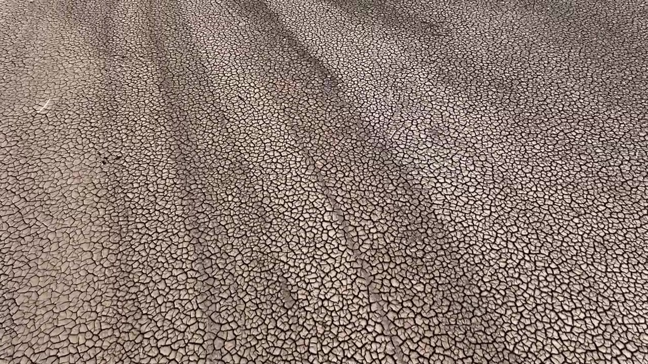 Cracked waterless land of lake in Spain during drought, aerial drone view