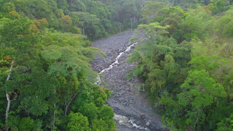 rio negro trickling waterway between dark rocks in clearing of dense tropical forest risaralda colombia, aerial establish