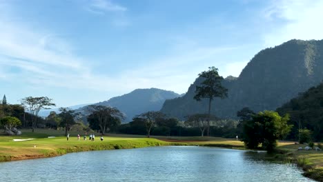 campo de golf panorámico con montañas y agua