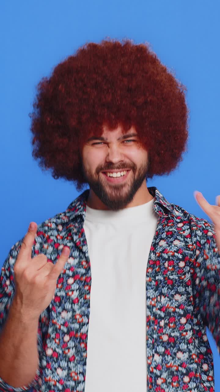 L'uomo felice e gioioso mostra il gesto del rock n roll con le mani fresche segno espressione pazza danza vittoria vittoria