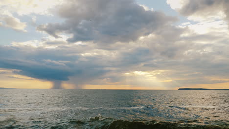 A-Rain-Cloud-With-Rain-Over-The-Sea-And-A-Setting-Sun-With-Beautiful-Rays