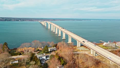 a sideways 4k aerial shot of a long bridge going through with water underneath