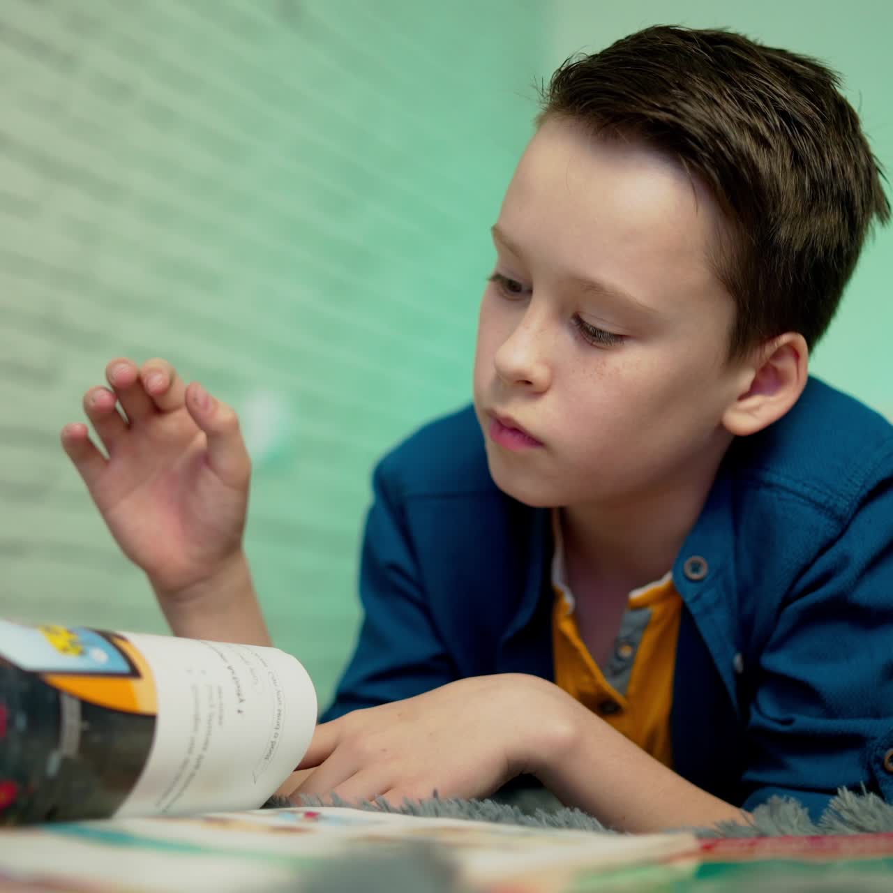 Little boy lying on bed reading book at home. Home education.