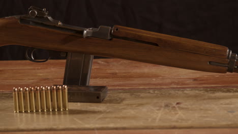 wide dolly of classic 30m1 carbine rifle with ammunition on the foreground standing on a wooden surface