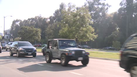 un automóvil viaja a lo largo de una calle en la ciudad del siglo de los ángeles, visto a través de la ventana trasera en un ángulo 7