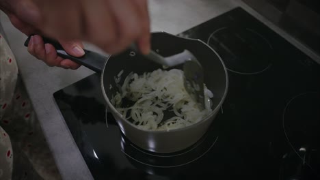 Niña-Guisando-Cebolla-En-Una-Olla-En-Una-Estufa-Eléctrica,-Cocinando,-Preparando-Comida,-Mezclando,-Revolviendo-Con-Cuchara-De-Plástico,-Preparando-Comida,-Alimentación-Saludable,-Almuerzo,-Cena,-Cocinando-Con-Aceite,-Haciendo-Un-Plato,-Primer-Plano