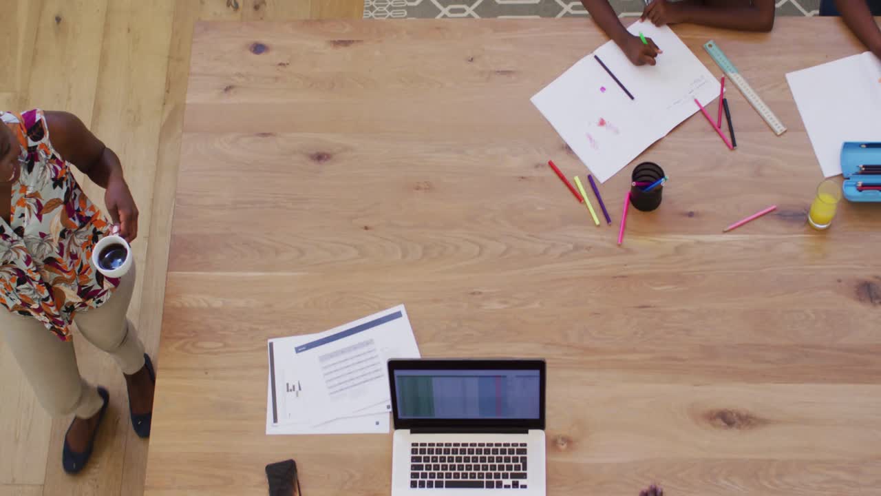 vista aérea de una mujer afroamericana dándole una taza de café a su marido en casa