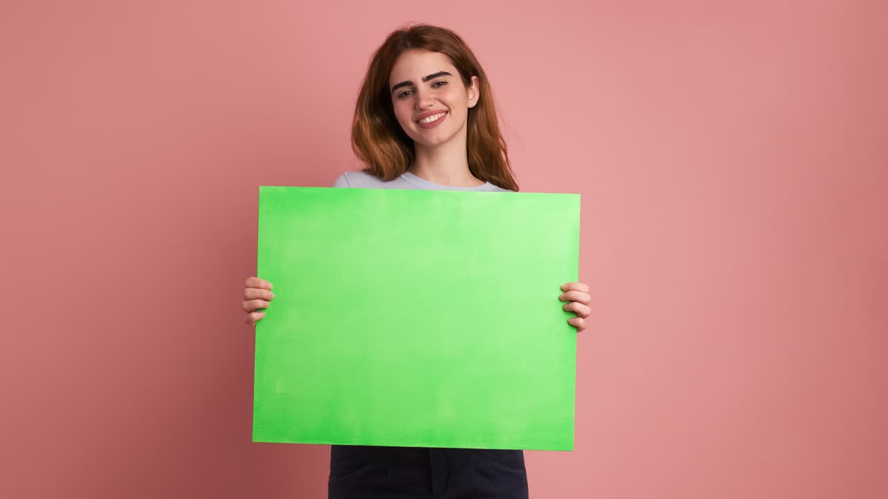 Smiling young woman holding a green board