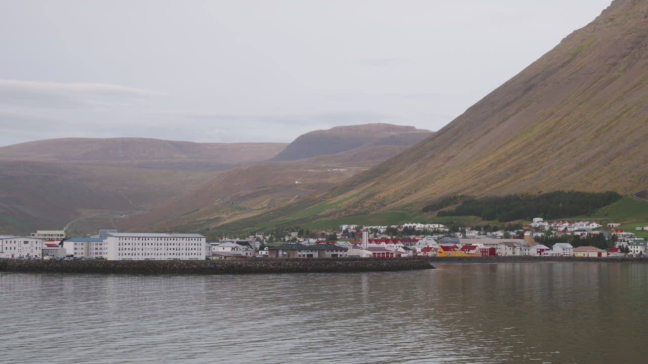 POV von einem Schiff, das an einem bewölkten Tag in den Hafen von Ísafjörður, Island, einfährt, ein kleines Fischerdorf.