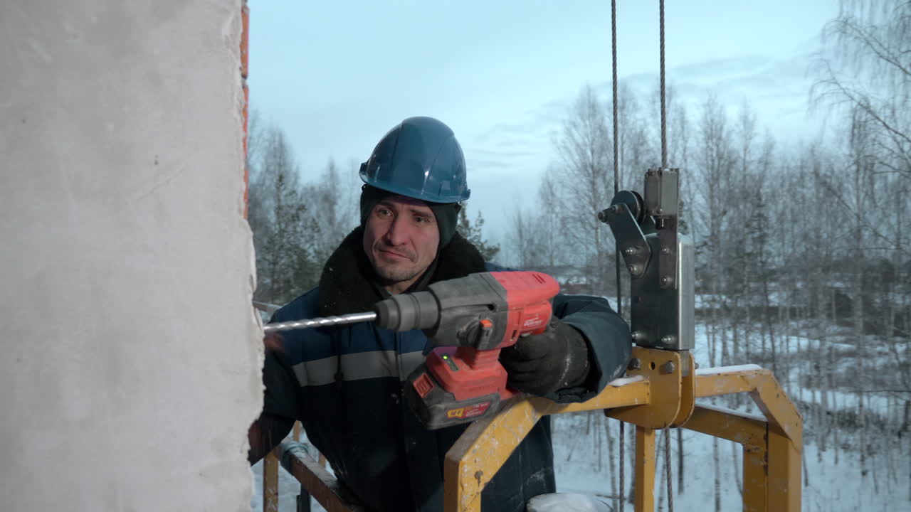 Byggnadsarbetare borrar en vägg på vintern