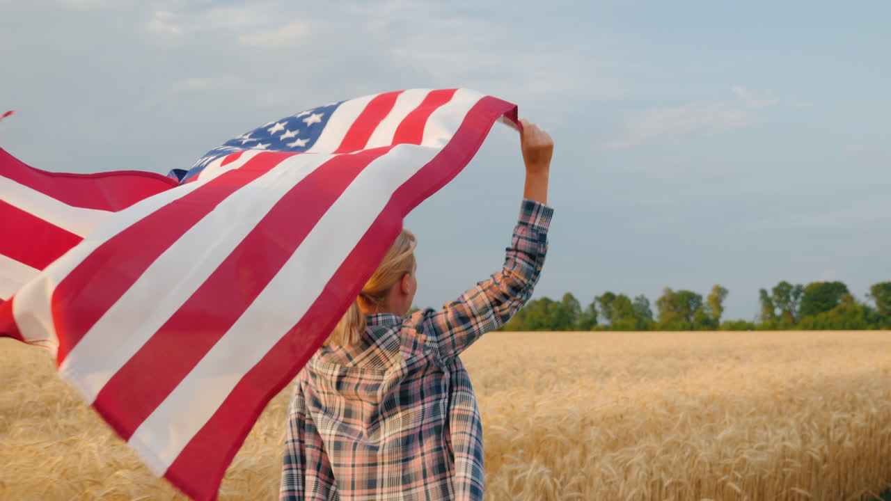 mujer con bandera de estados unidos corre bajo el sol en un campo de trigo