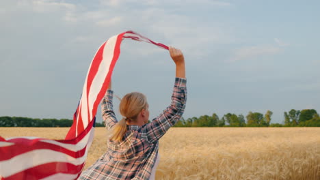 kobieta z flagą usa biegnie w słońcu na polu pszenicy