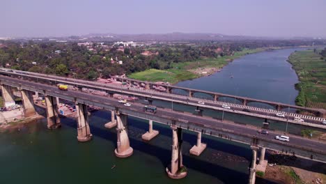 vehicles are moving on tilwara narmada river bridge with trees and light poles at jotpur, madhya pradesh, india. day time, semi orbit, push down, drone shot, 4k.