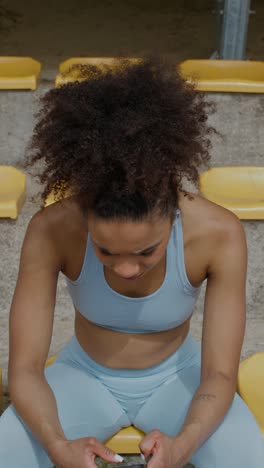 woman resting and using phone at stadium