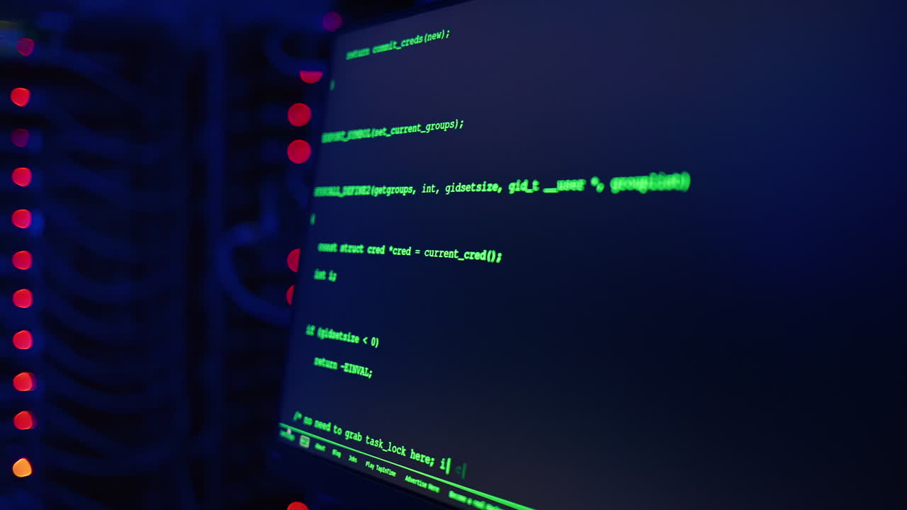 Close up of code on a screen in a server room with flashing red lights