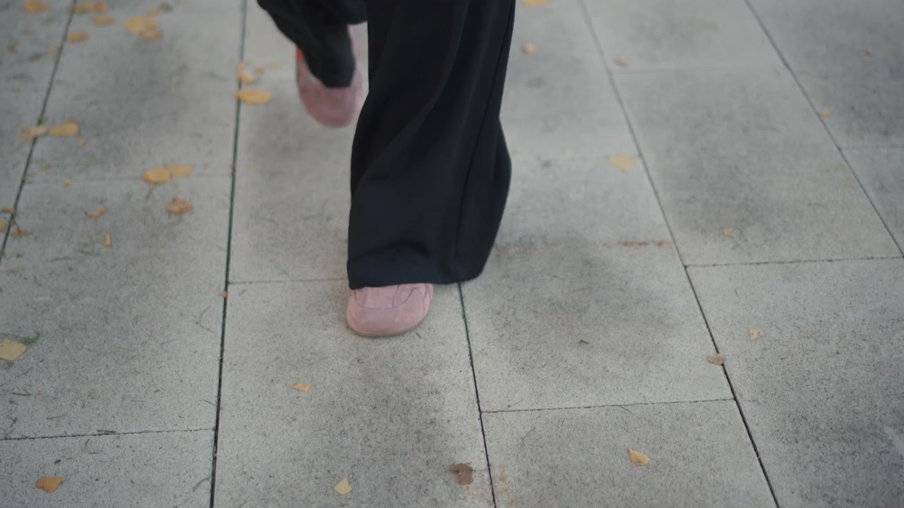 Person Walking in Black Trousers and Pink Sneakers on Paved Path