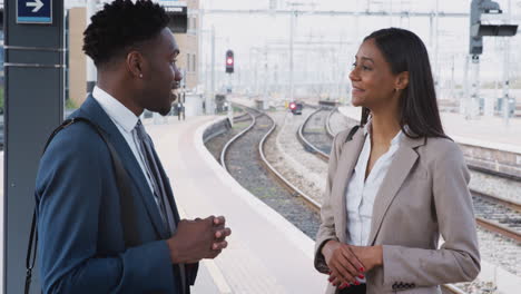 businessman and businesswoman commuting to work talking on railway platform waiting for train