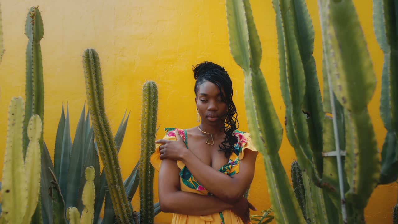 Donna elegante in abito giallo tra i cactus
