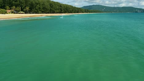 4k cinematic nature aerial footage of a drone flying over the beautiful beach of bang tao in phuket, thailand on a sunny day