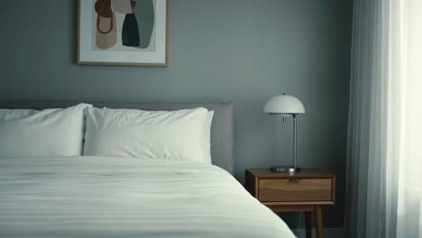 a serene modern bedroom scene with elegant bedding and stylish nightstand lamp, offering a calm and inviting atmosphere by daylight