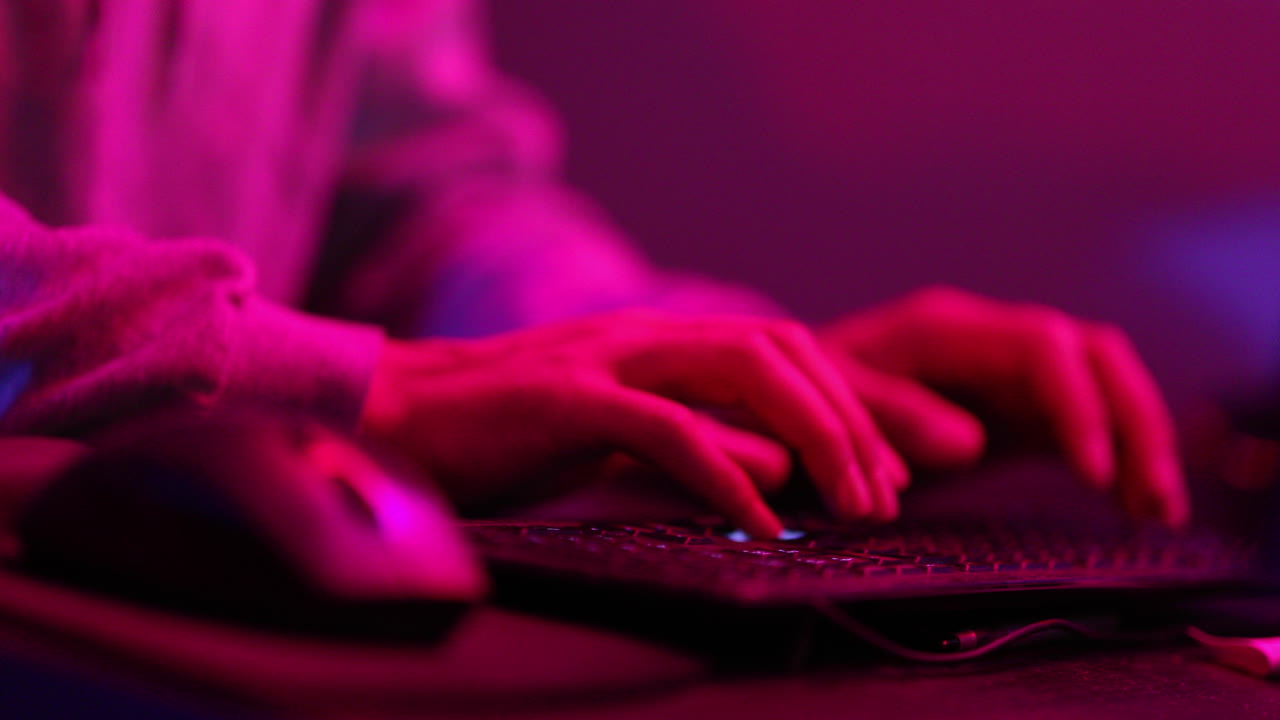 Person typing and possible hacking a system in an alarming red and blue room