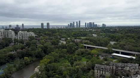 drone flying over green space with a river running through it in downtown toronto with a highway in the distance