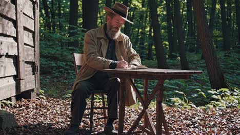 a man stands in a sunlit forest clearing near a cabin, captured from a low-angle shot