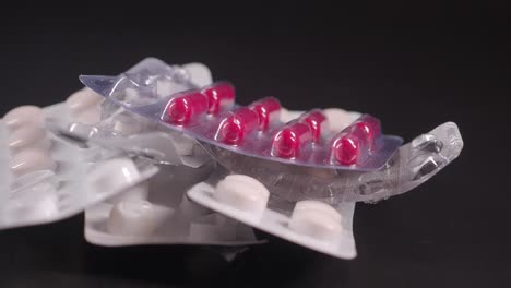 a pile of pill blister packs with some red capsules and white pills