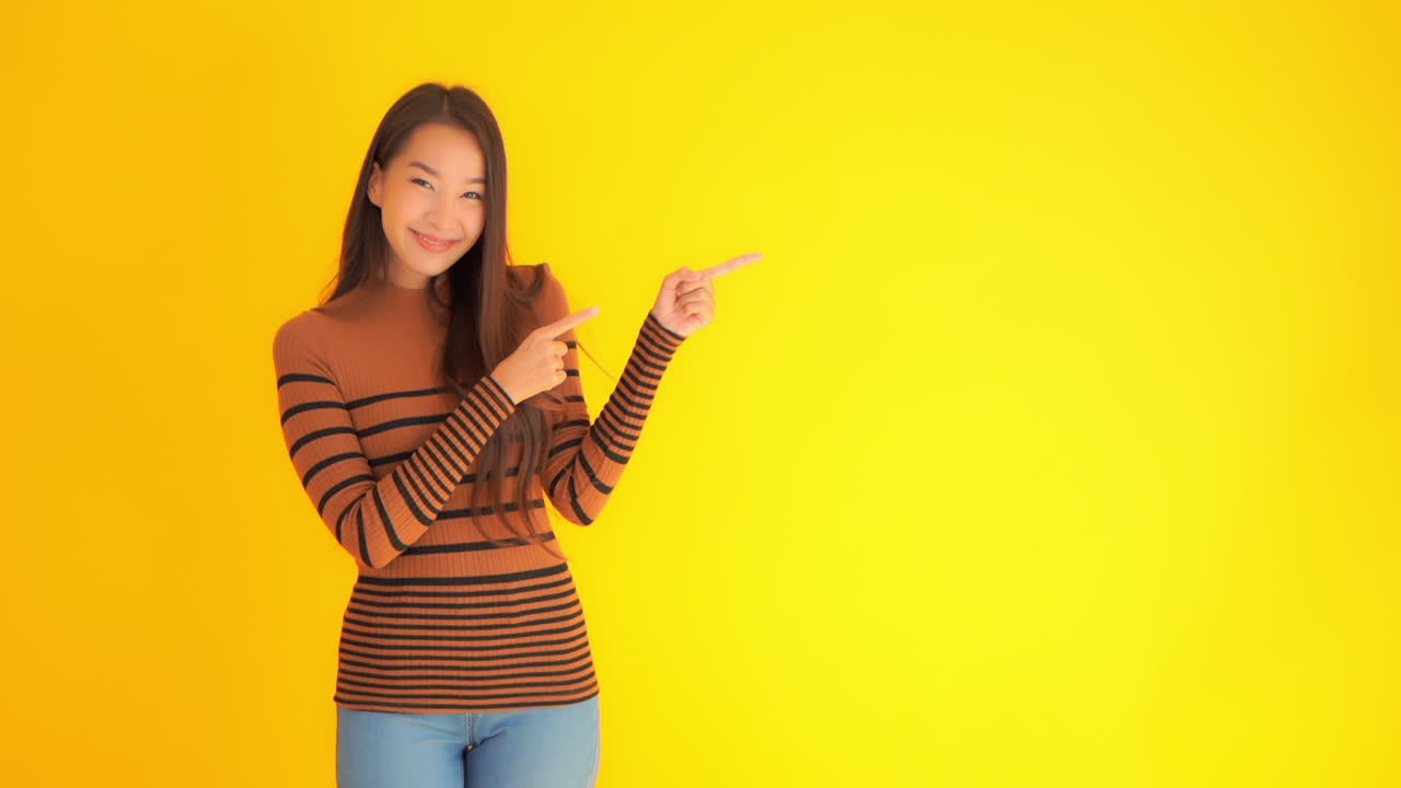 Smuk kvinde peger på kopiområde til tekst på gul baggrund i slowmotion