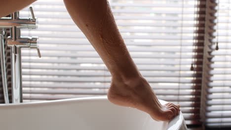 woman scrubbing her legs in a bathtub