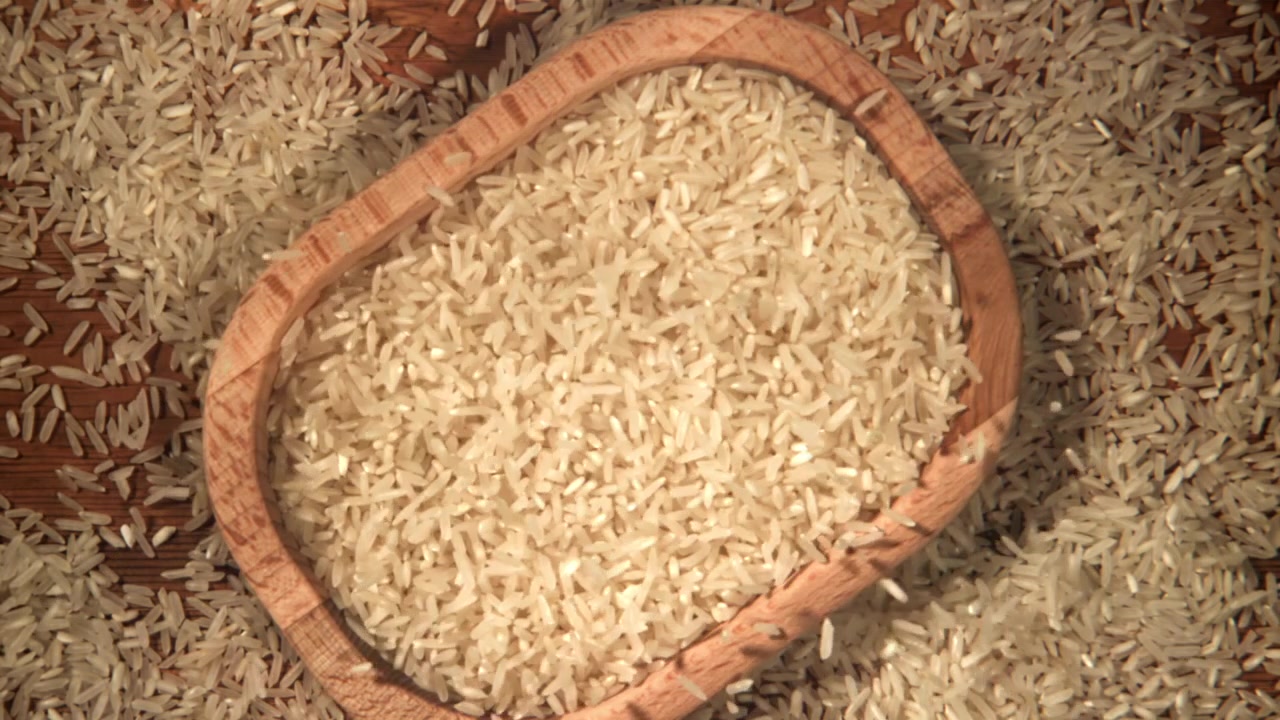 Riso bianco che cade al rallentatore in una ciotola di legno
