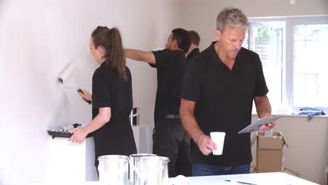 decorating team painting walls and using digital tablet