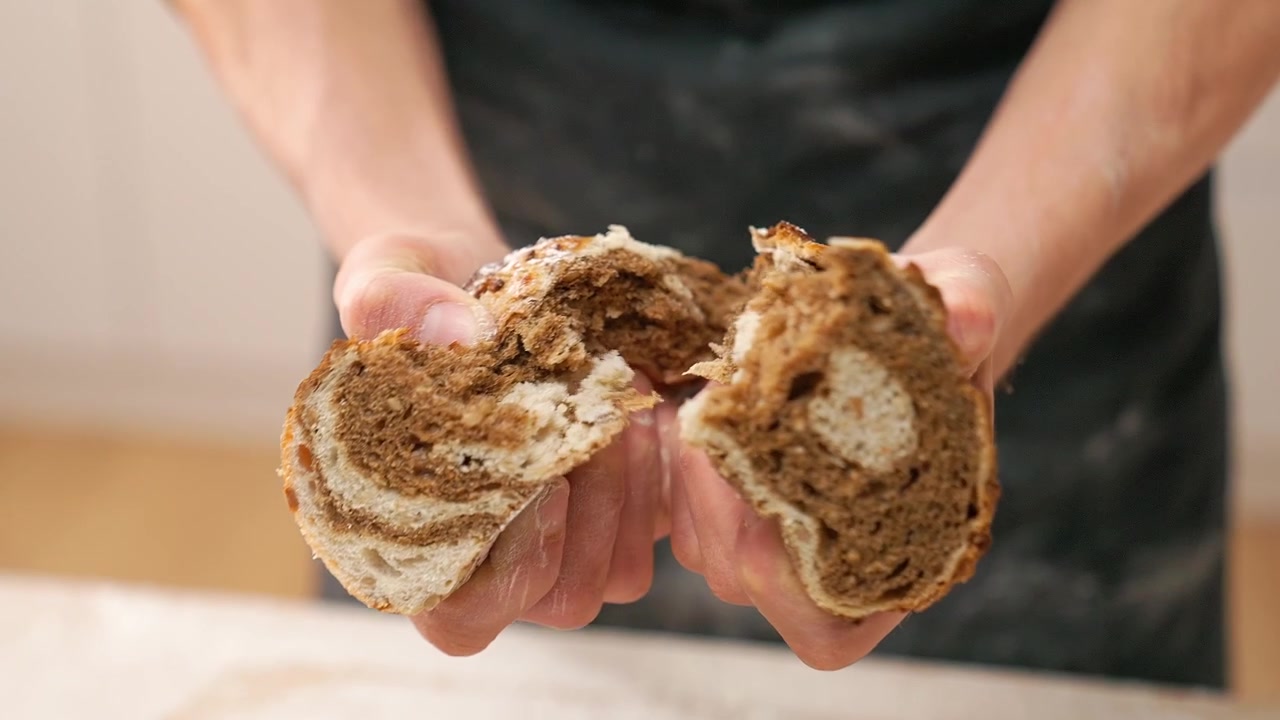 Close-up of Hands Breaking a Freshly Baked Nut Roll