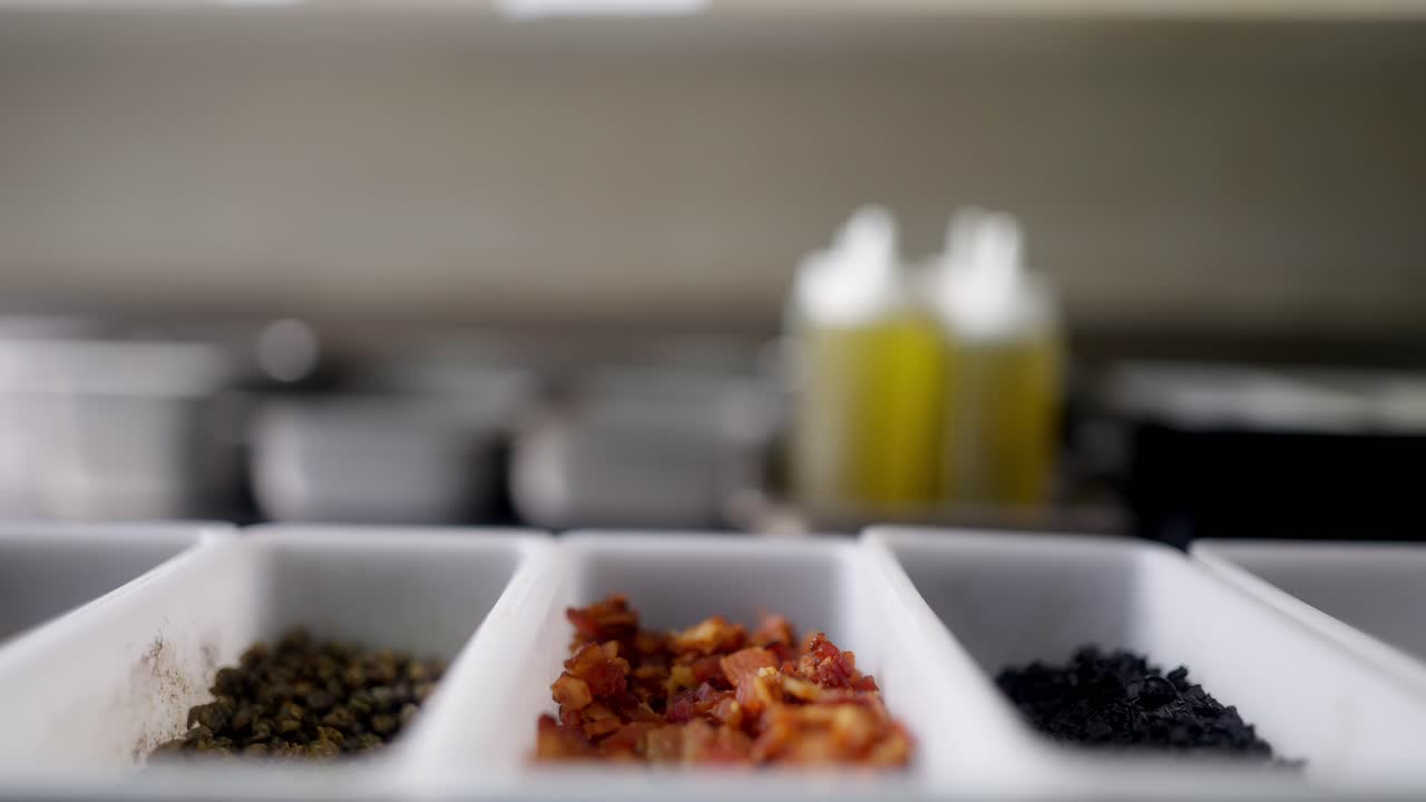 Slow motion and close up view of bacon bits falling in an ingredients container.