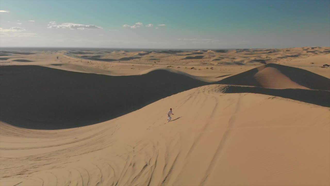 antena de dunas de arena del desierto con motocross y un hombre corriendo