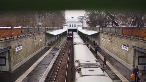 dolly shot over train pulling up to the station blurry green rails foreground