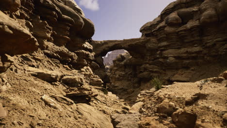 arid landscape with rock formations and a natural arch under clear skies