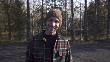 cheerful traveler smiling at camera in forest