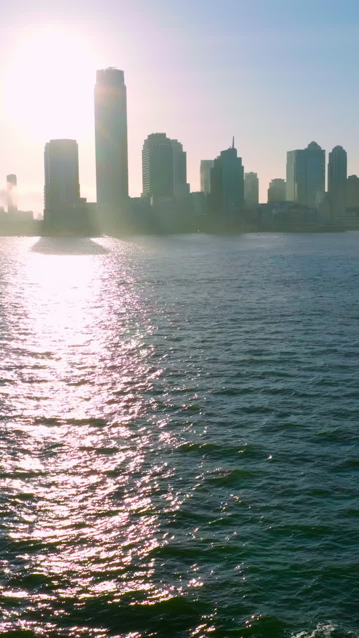 Dark waters of East River with fantastic sun path on. Dark silhouette of skyscrapers towering over Manhattan Island. Vertical video