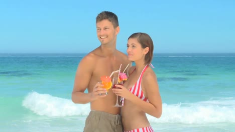 dulce pareja compartiendo cócteles en una playa