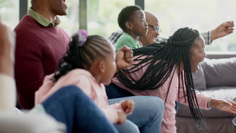 excited african american parents, son, daughter and grandparents watching sport on tv, slow motion