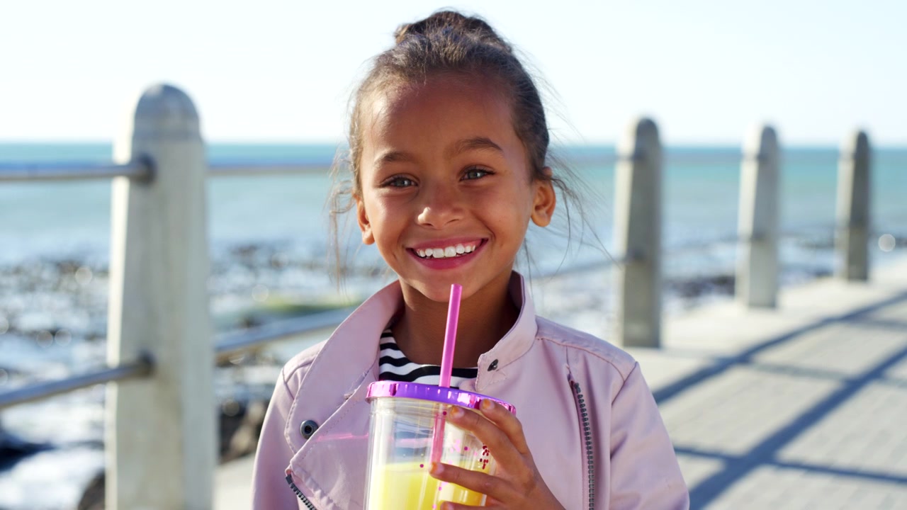 Young Girl Drinking Juice on a Sunny Seaside Promenade