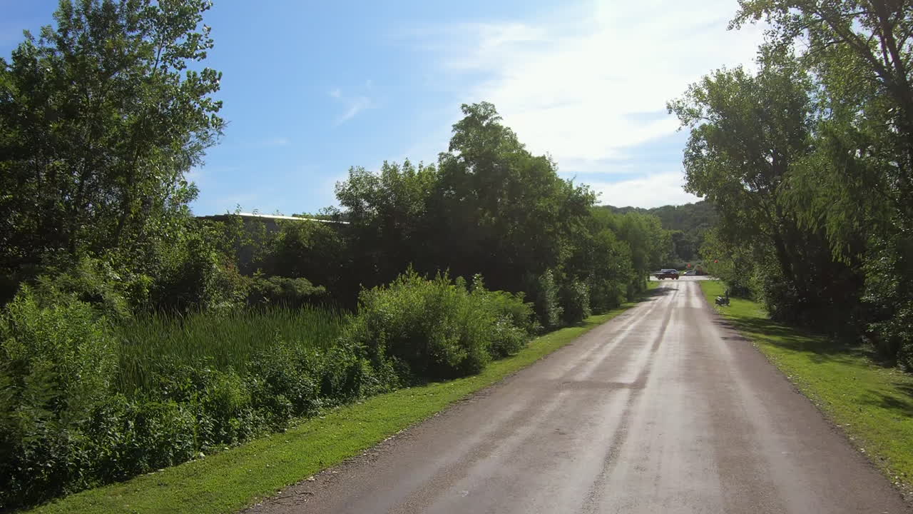 밝은 여름날 자란 덤불과 나무로 둘러싸인 뒷길에서 운전하는 포브