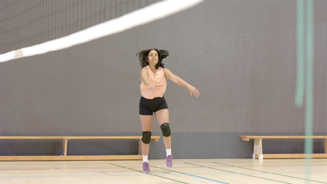 Atlet Wanita Melakukan Passing Bawah, Mengumpan, dan Melakukan Smes Bola setelah Pasangan Melemparkannya melewati Net di Gimnasium, dengan Ruang Kosong