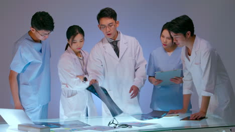 professional expert doctor talking with medical staff having meeting holding radiography x-ray. clinic therapist discussing with colleagues about disease, healthcare concept