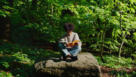 person reading a book in a forest