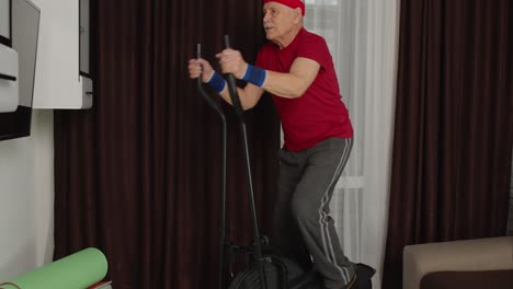 anciano anciano modelo de abuelo saludable haciendo ejercicio deportivo entrenamiento en orbitrek en la habitación en casa