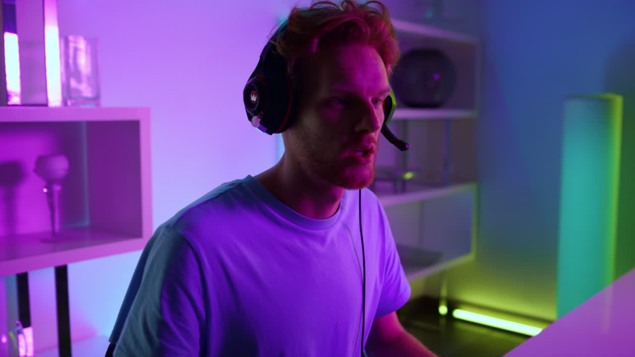 Closeup cyber man playing video game in headset. Neon computer equipment at home